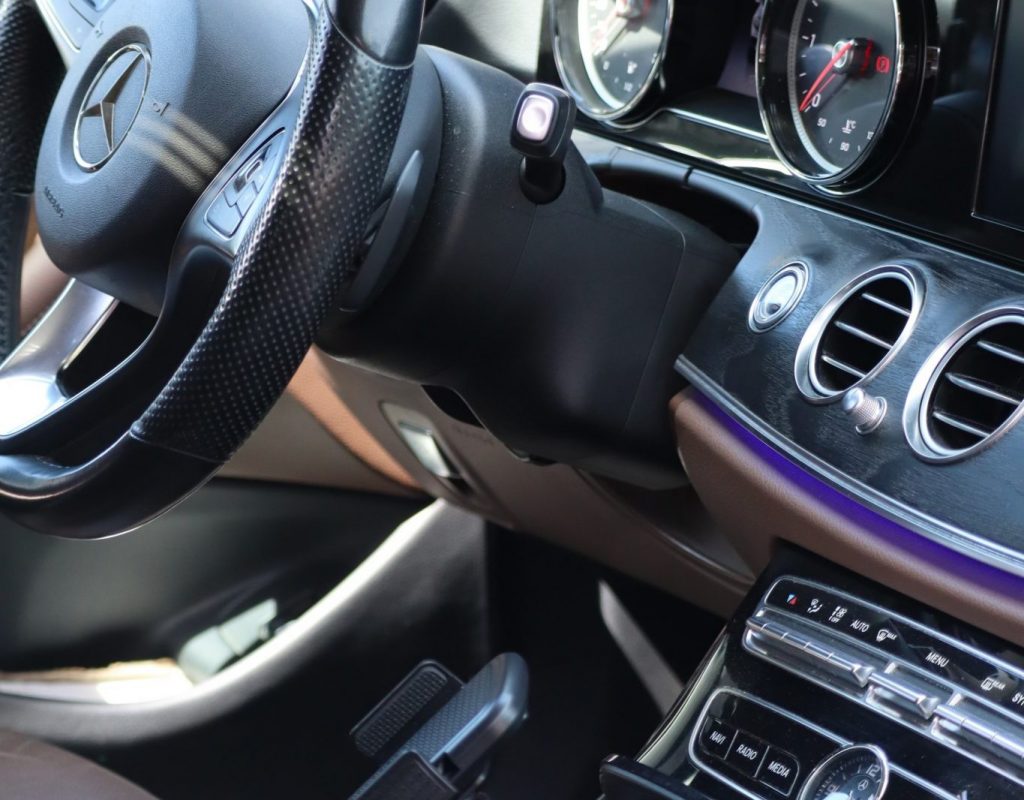 Photo de l'intérieur d'une voiture, vue sur le tableau de bord, le volant ainsi que la boîte de vitesse.